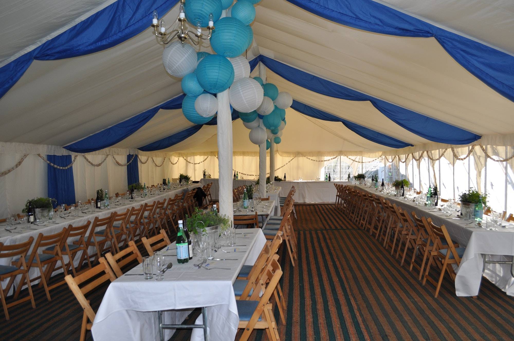 Wedding reception held in a huge tent decorated with balloons and blue and white curtains.