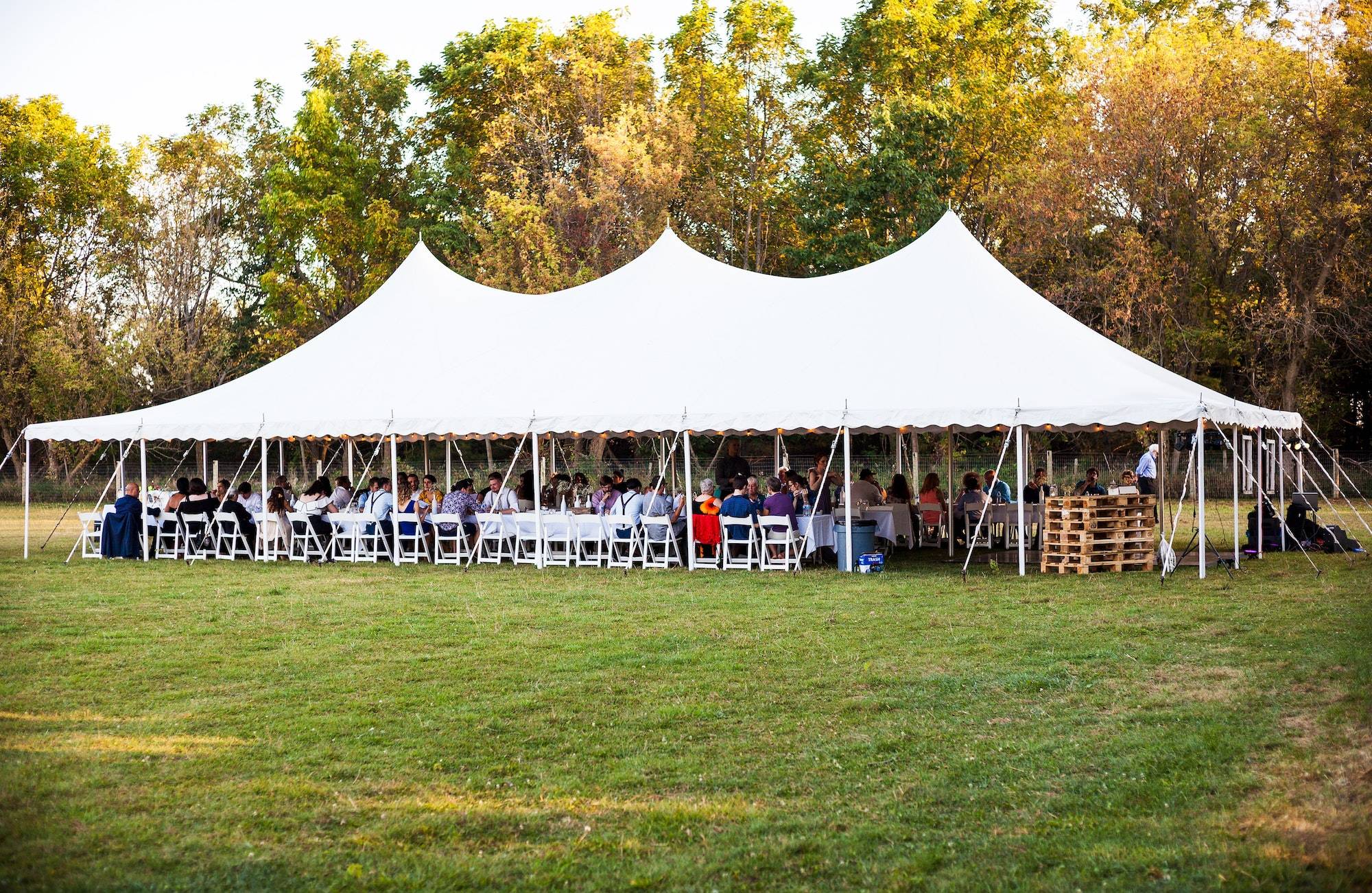 white outdoor tent full of tables and people seated